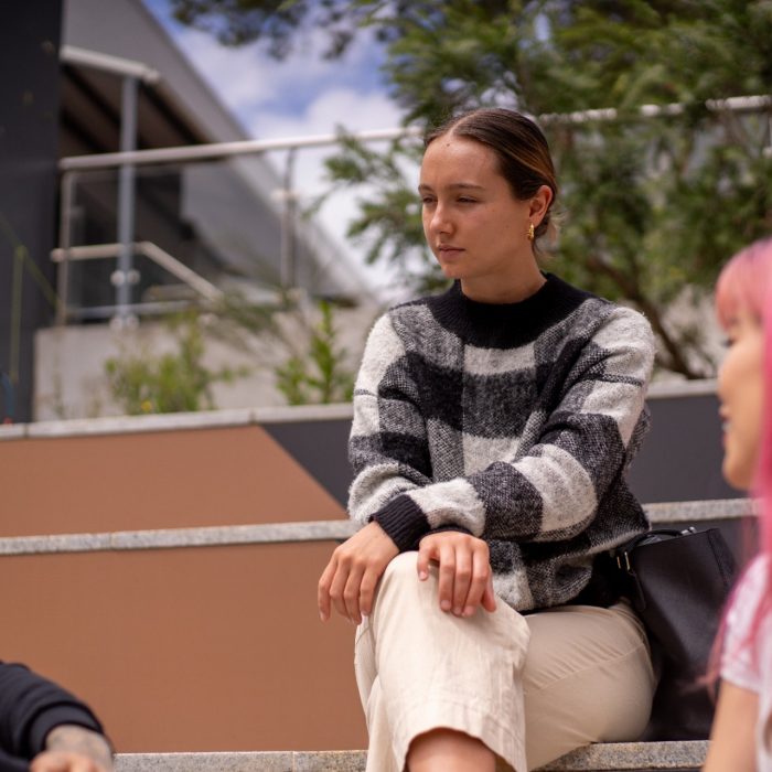 Three students chatting while sitting on the steps outdoors on Paddington Campus