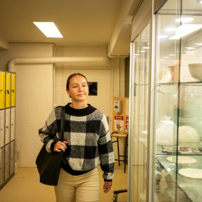 Students chatting while walking alongside glass cabinets on Paddington Campus
