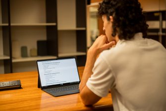 Students using their laptops at a shared desk in the library