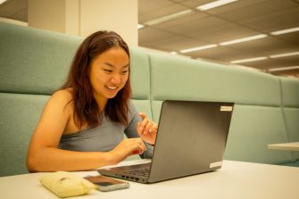 Students using their laptops at a shared desk in the library