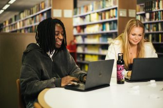 Students on their laptops sitting in a common study space