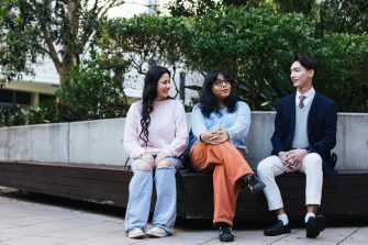 Three students sitting together on campus chatting
