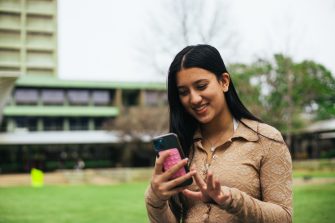 Students looking at their phones on Library Lawn