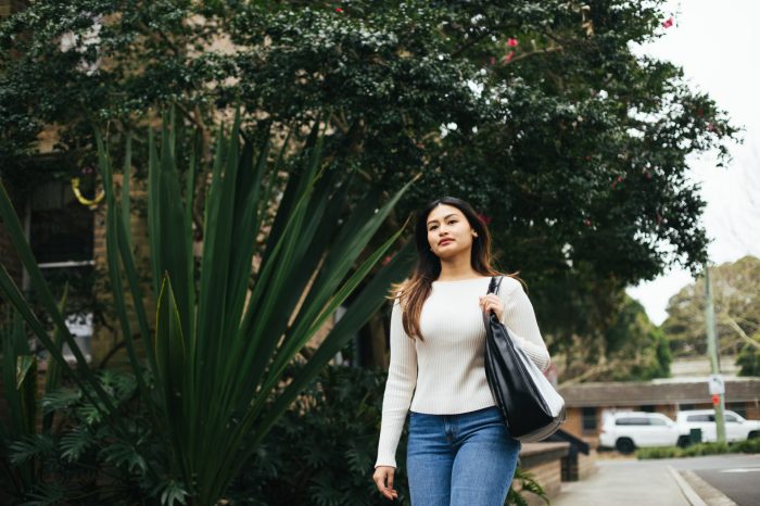 Student walking on campus with the Chancellery building in the background