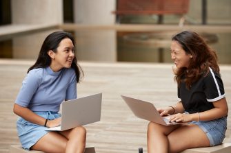 Two students sit together to work through assignments