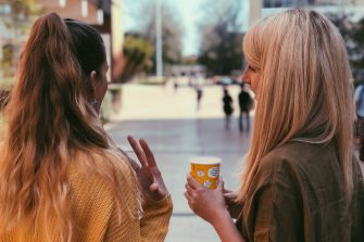 Two students photographed from behind engaged in discussion on campus