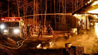 Firefighters putting out a burning cabin in the woods