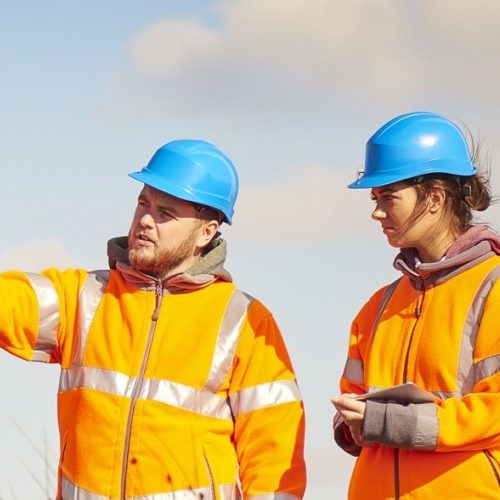 Two engineers assessing something in the distance on site