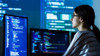 Software developer freelancer woman female in glasses work with program code C++ Java Javascript on wide displays at night Develops new web desktop mobile application or framework Projector background