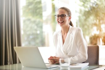 A woman smiling infront of her laptop