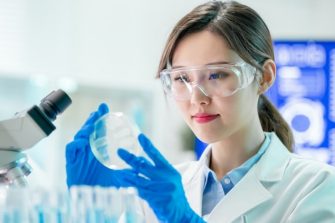 A researcher examining a petrie dish in a laboratory