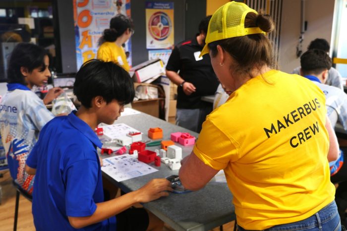 A UNSW Makerbus crew member assists a student at Dripstone Middle School in Darwin to make and program a dancing robot.