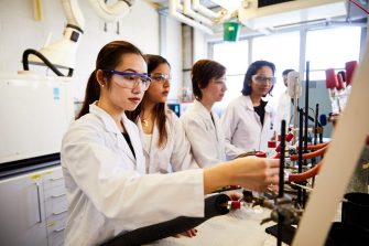Engineering students wearing safety gear and working in chemistry lab