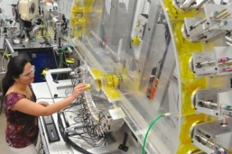Female engineer inserting yellow cylinder into lab machine