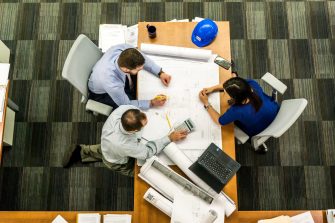 three people shot from above working on design schematics in an office