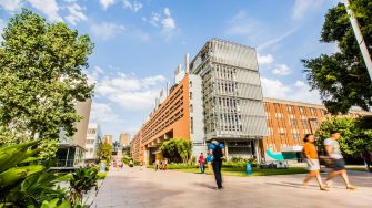 Students walk along the University Mall with the Red Centre in the background