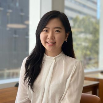 A headshot of Sohyun Lee with a white shirt on, sitting in front of large window. 