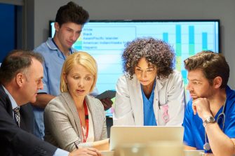 a mixed group of healthcare professional and business people meet around a conference table .