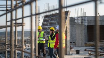 Construction workers standing on outdoor construction site and discuss the building plans