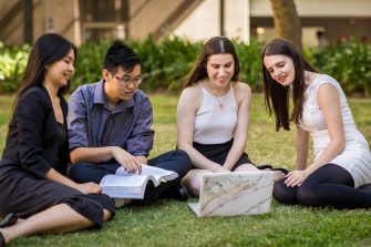 4 UNSW students sitting on a lawn on campus