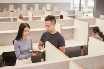 Students walking past bookcases at the law library UNSW.