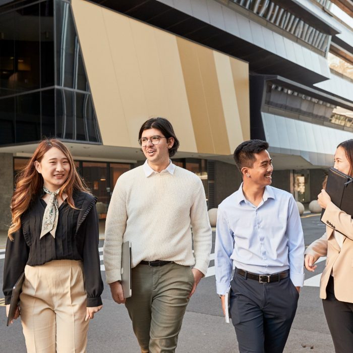 Group of law students walking behind law building, smiling and laughing, smart casual attire