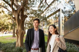 Law student couple standing together in front of Law Building, trees and greenary in background