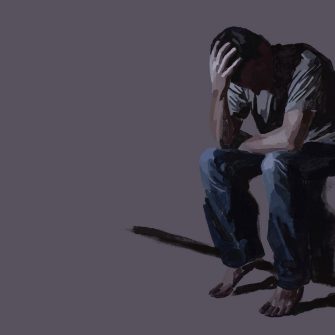 a boy sitting down and holding his head