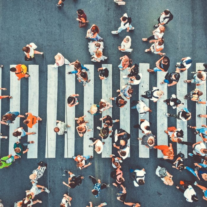 Aerial. People crowd on pedestrian crosswalk. Top view background. Toned image.