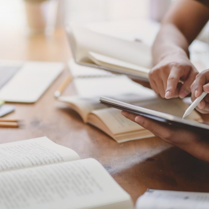 Close-up view of university students discussing their group project while using tablet 