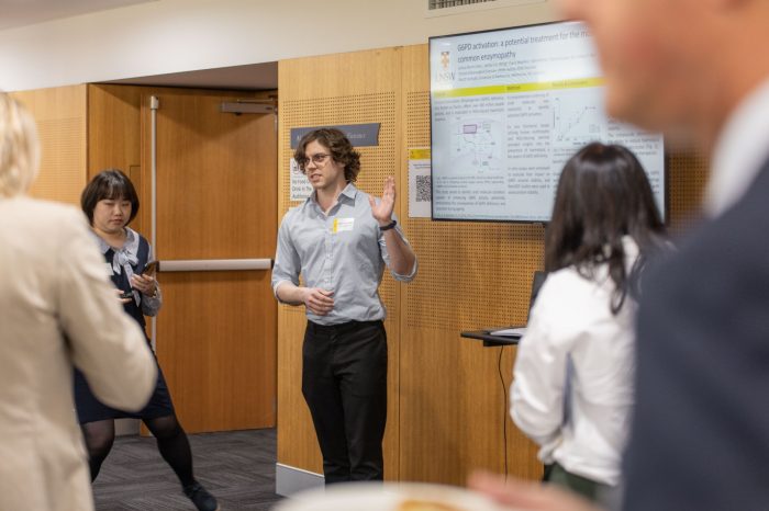 Researcher presenting his poster to an audience