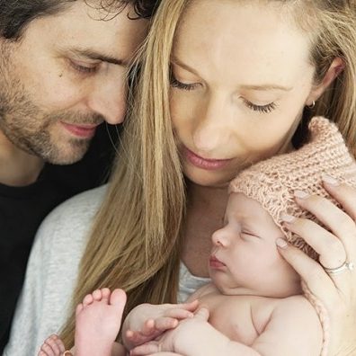 Two people holding a small baby