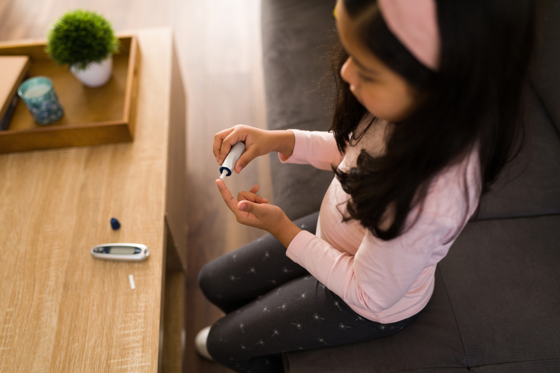Young girl using a digital monitor to test her blood sugar levels at home