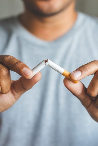 A man breaks a cigarette after deciding to quit smoking.