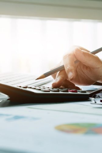 Close up Business woman using calculator and laptop for do math finance on wooden desk in office and business working background, tax, accounting, statistics and analytic research concept