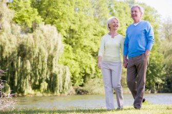 Older couple walking beside a river holding hands