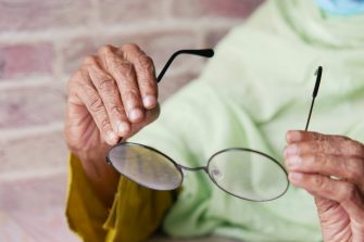 Older person holding their glasses