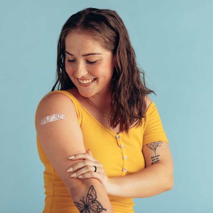 Woman looking at her arm with band-aid after receiving vaccine dose. 