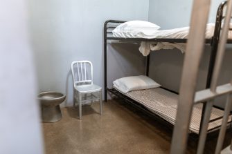 A Bunk Bed With Striped Foam Mattress in a Prison Cell