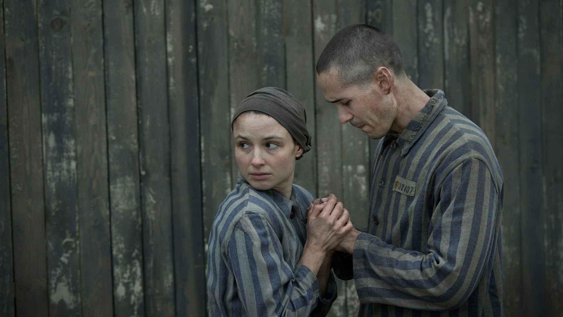 female and male Jewish prisoners at Auschwitz hold hands in fear 