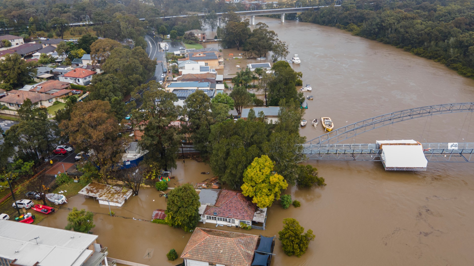 Houses beside the Georges River are engulfed by brown flood water