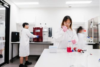 Wide shot of 3 lab staff in lab working on various processes