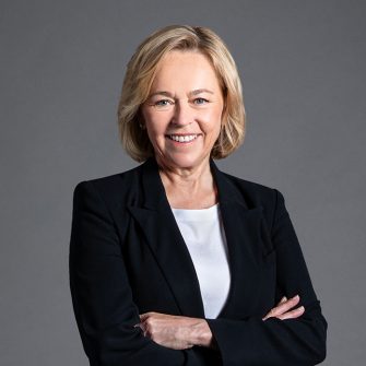 Headshot of a moddle-aged blonde woman with a tidy bob in a black blazer and white shirt