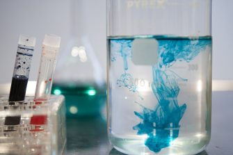 a beaker fill with colouring dispersing in clear liquid inside
