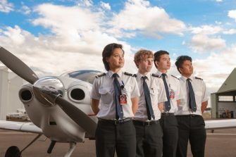 Four students standing in front of an airport