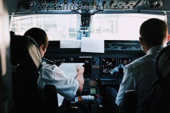 Two pilots sitting in a plane going through a checklist