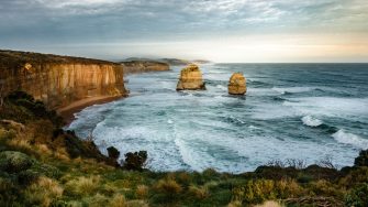 Rock formations on sea under cloudy sky