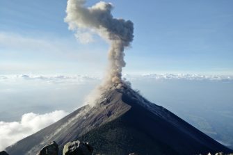 Smoking volcano with clouds and in the background