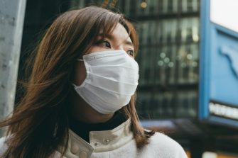 Young woman wearing a protective face mask to prevent the spread of germs and viruses in the city