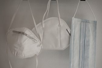 Three masks hanging on hooks on a wall